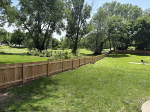 A long stretch of newly installed wooden privacy fence in a large backyard by Fry's Fence LLC in Grain Valley, MO.