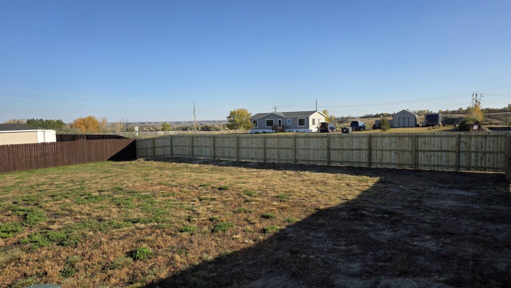 A long, well-built wooden privacy fence defining a residential backyard, installed by Row Fencing and Services in Williston, ND.