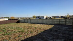 A long, well-built wooden privacy fence defining a residential backyard, installed by Row Fencing and Services in Williston, ND.