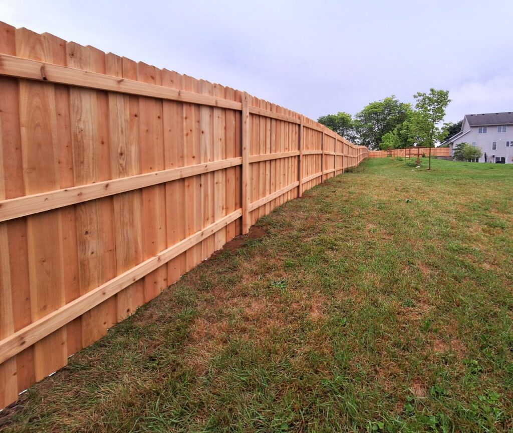 A long, newly installed wooden privacy fence in a residential backyard by Smith & Company Custom Fence LLC in Niles, MI.
