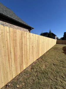 A long, newly installed wooden privacy fence enclosing a backyard by Timber Wolf Fence Co. in Rogers, AR.