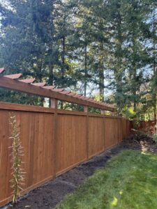 A long, newly installed wooden privacy fence with a decorative top, built by Fences NW LLC in Spanaway, WA