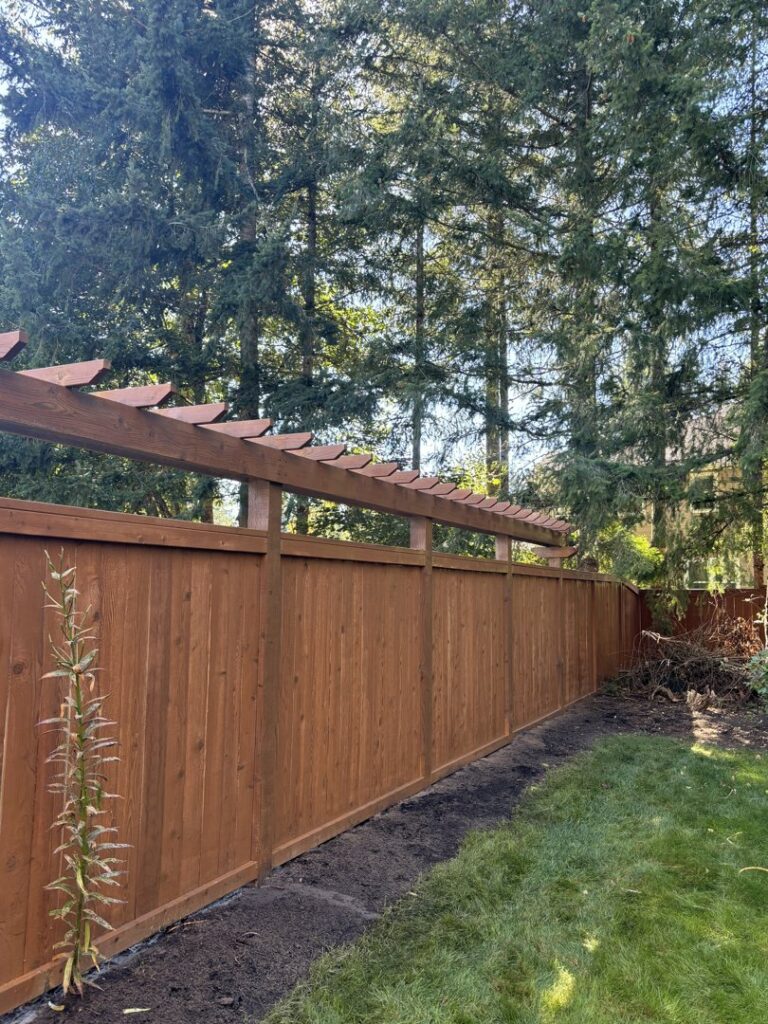 A long, newly installed wooden privacy fence with a decorative top, built by Fences NW LLC in Spanaway, WA