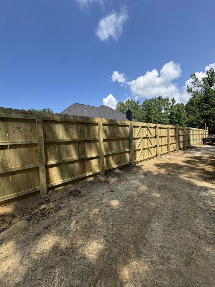 A long stretch of newly installed wooden privacy fence with a gate, completed by Littleton Construction LLC in the Service Area.