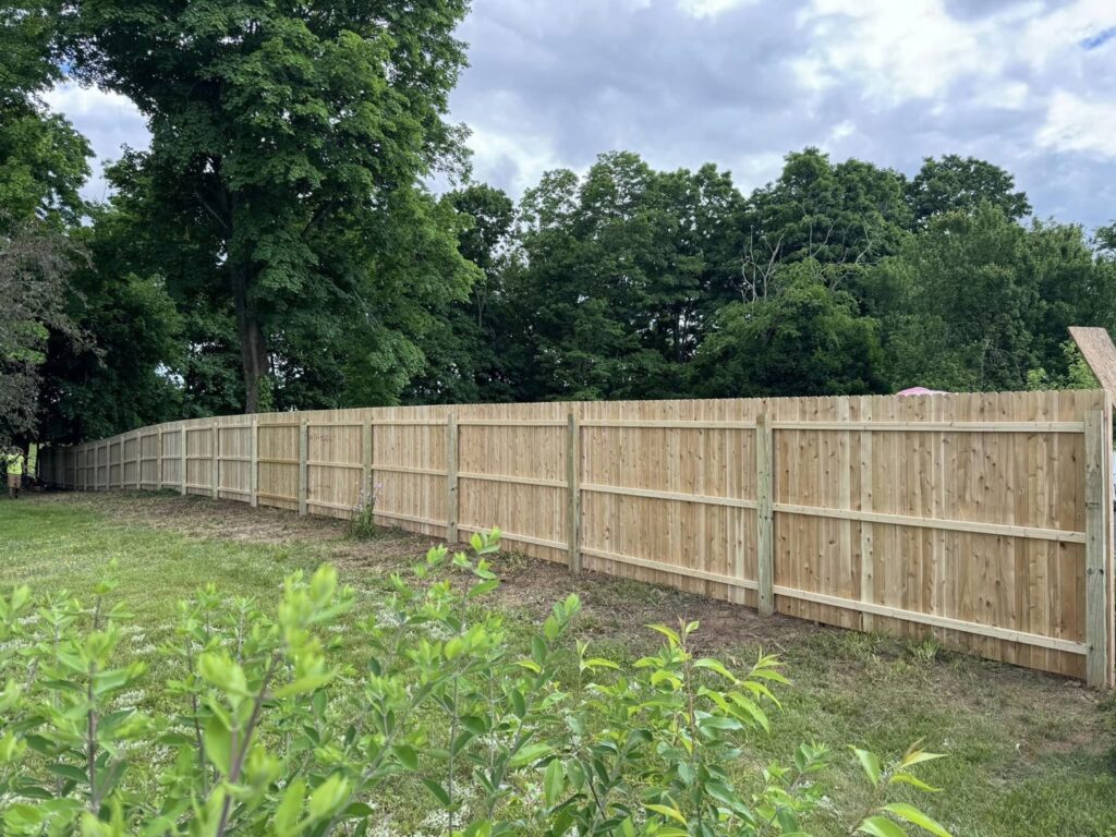Long wooden privacy fence installed along a residential property by Select Fence & Guardrail in North Haven, CT.