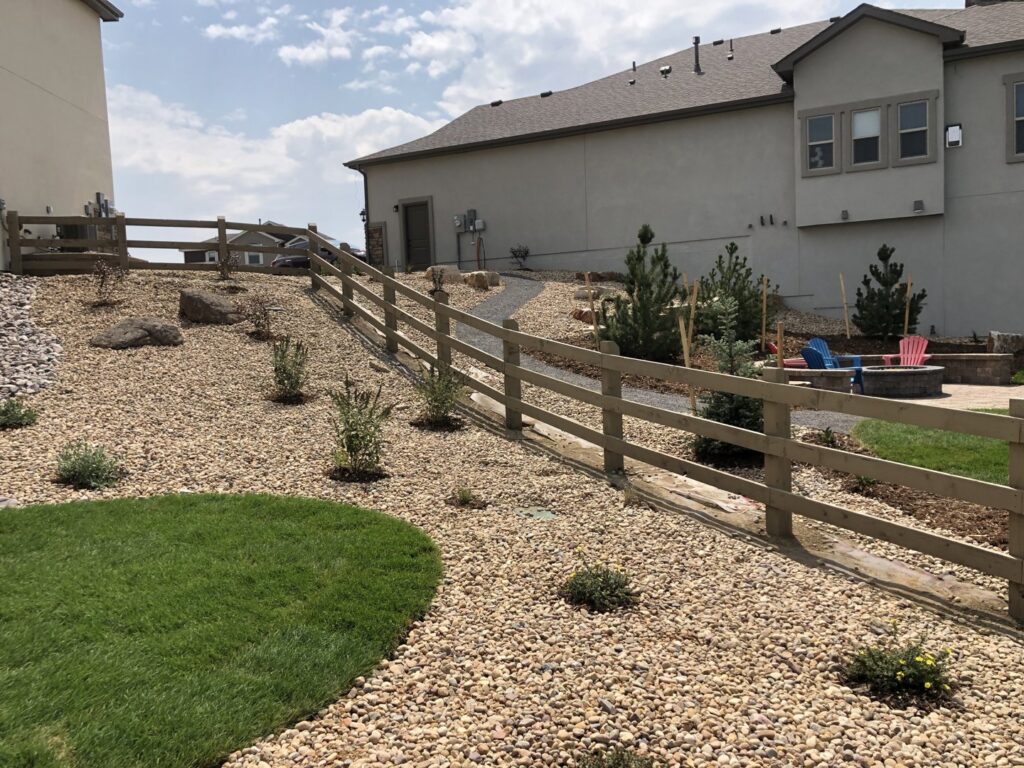 A long wooden split-rail fence installed on a sloped backyard landscape by North CO Fence & Deck in Greeley, CO.