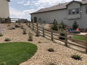 A long wooden split-rail fence installed on a sloped backyard landscape by North CO Fence & Deck in Greeley, CO.