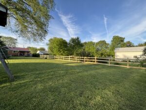 A long wooden split-rail fence with wire mesh installed in a large grassy area by D&M Renovation Services LLC in Columbus, OH.