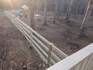 A long wooden split rail fence with wire mesh installed around a large backyard by Sunrise Fences in Monroe, NC.
