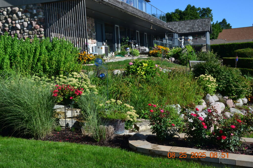 A lush garden with various plants and flowers, complemented by a well-maintained lawn by Miguel Landscaping LLC in Janesville, WI.