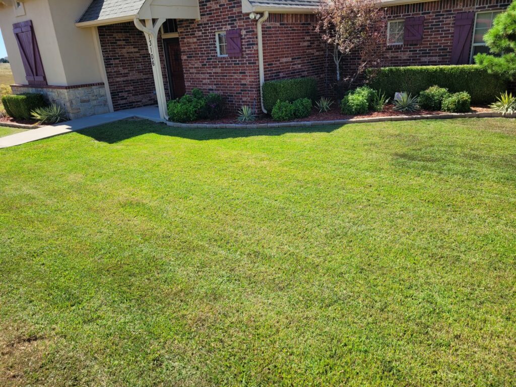 A beautifully maintained, lush green lawn with trimmed bushes by R & W Lawn care service LLC in Tulsa, OK.