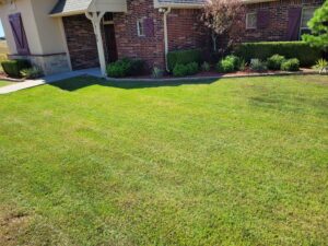 A beautifully maintained, lush green lawn with trimmed bushes by R & W Lawn care service LLC in Tulsa, OK.