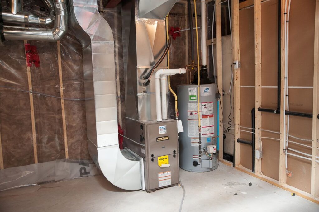 A Luxaire furnace and water heater with ductwork and piping installed in a utility room by Douglas Cooling & Heating in Pelham, AL.