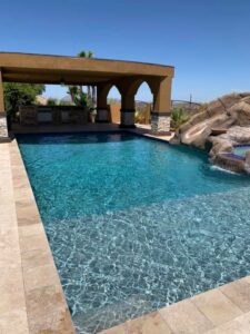 A luxurious, clean pool with an adjacent outdoor kitchen area, showcasing excellent pool maintenance by Space Ranger Pools in Gilbert, AZ.