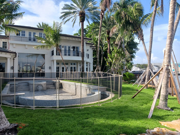 A light-colored mesh pool safety fence installed around a luxury home's pool by All Brand Pool Fence in Fort Lauderdale, FL.
