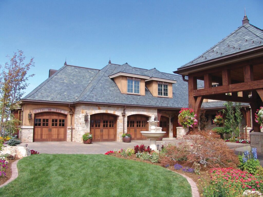 Luxury home featuring multiple wooden garage doors, showcasing an installation by CCM Overhead Doors in Oklahoma City, OK.