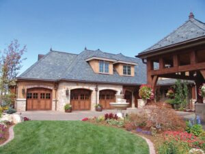 Luxury home featuring multiple wooden garage doors, showcasing an installation by CCM Overhead Doors in Oklahoma City, OK.