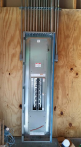 A main electrical distribution panel with conduits installed on a plywood wall by Ready Electric 24/7 in Knoxville, TN.