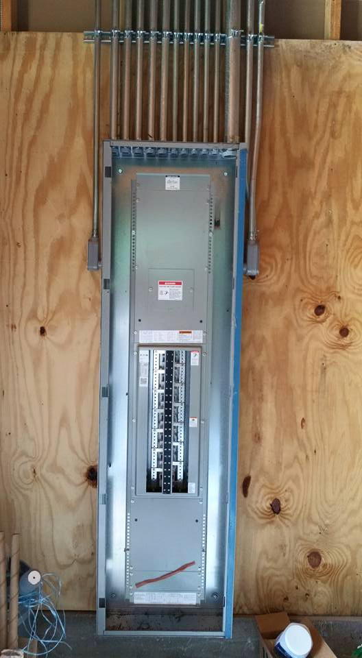 A main electrical distribution panel with conduits installed on a plywood wall by Ready Electric 24/7 in Knoxville, TN.