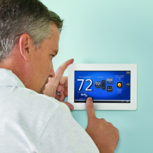 A man adjusting a smart thermostat for optimal home comfort with services from Air Doctors Heating and Air Conditioning in Kenosha, WI.