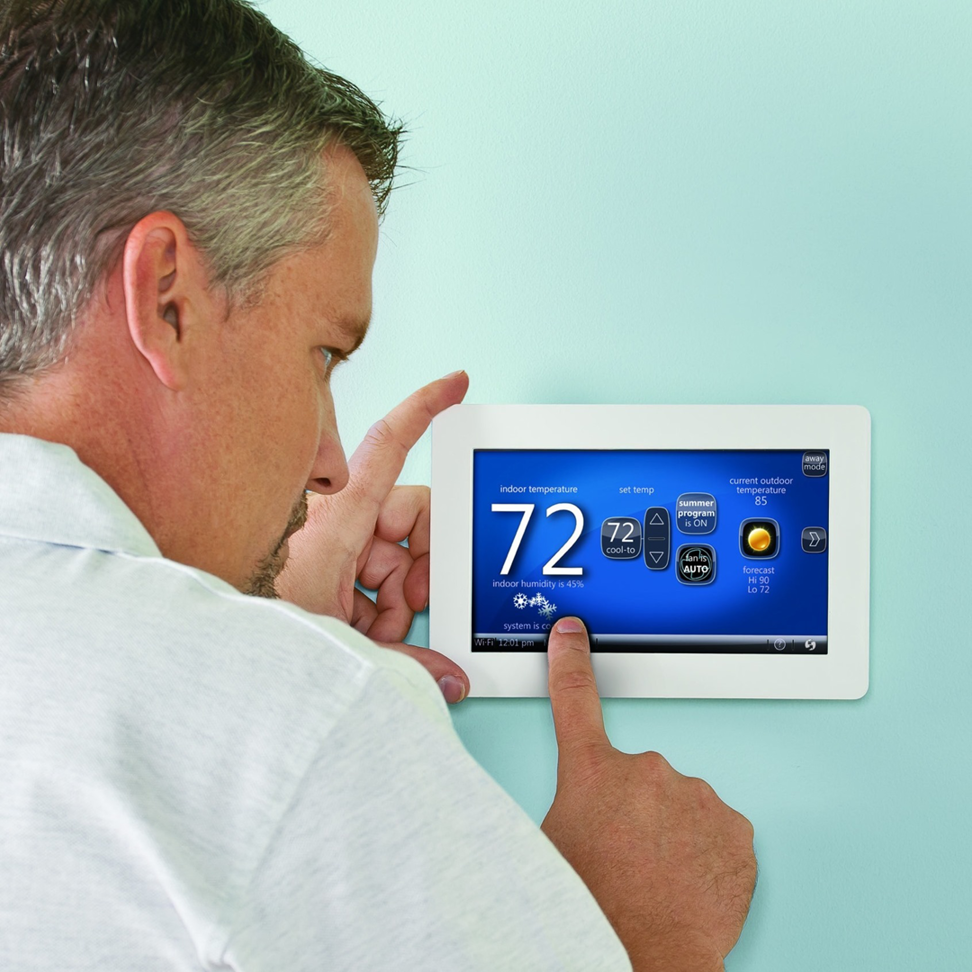 A man adjusting a smart thermostat for optimal home comfort with services from Air Doctors Heating and Air Conditioning in Kenosha, WI.