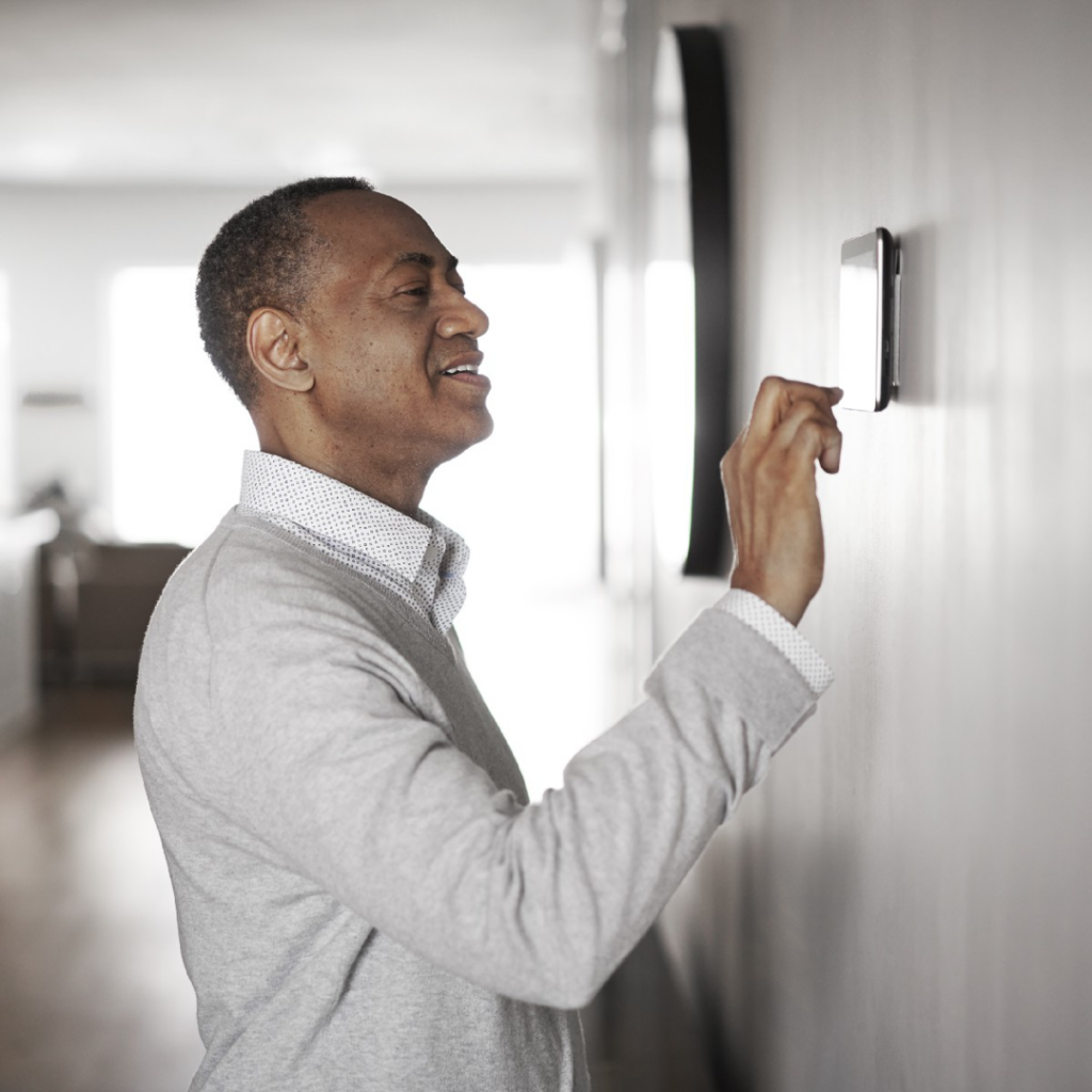 A man adjusting a smart thermostat, representing modern HVAC control by Apollo Heating and Air in Bellevue, NE.