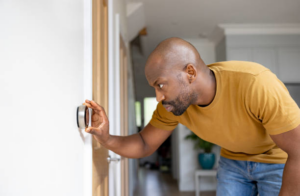 A man adjusting a smart thermostat for optimal home comfort and HVAC control with Texas Air Authorities, Inc. in Arlington, TX.
