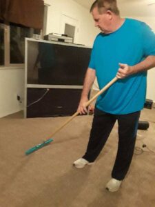 A man professionally cleaning a carpet with a specialized tool, demonstrating services by Ogden Carpet Cleaners in Ogden, UT.