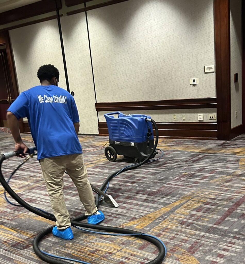 A man from 2themax Services LLC cleaning a large conference hall carpet in Carmel, IN.