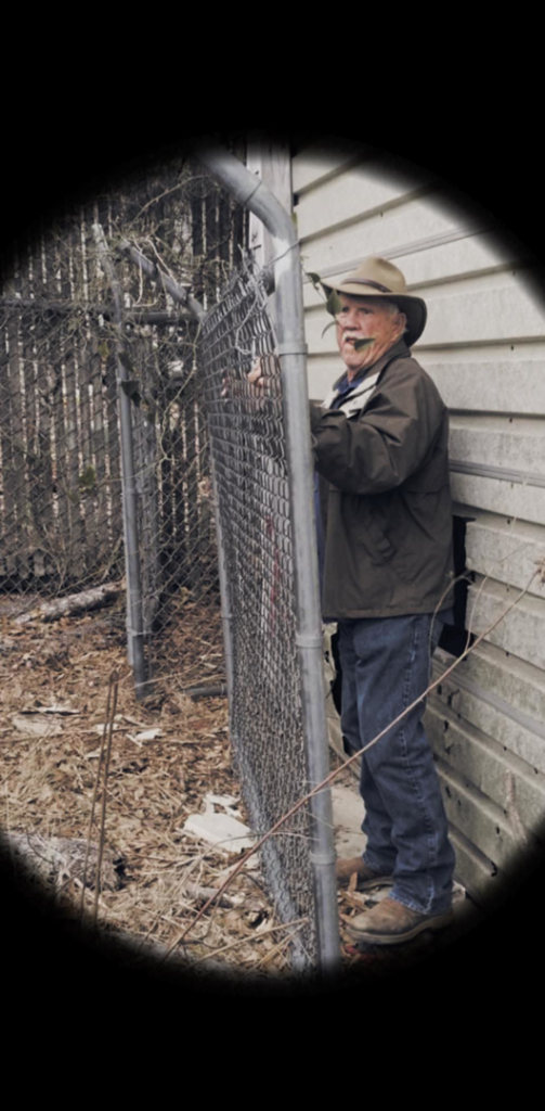 A man inspecting a newly installed or repaired chain-link fence by Southwest Fence Company Inc in Weatherford, OK.