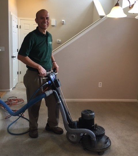 A man operating a professional carpet cleaning machine on a residential carpet at Declare It Clean in Aurora, CO