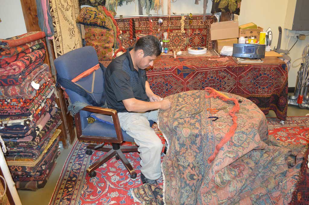 A skilled craftsman repairing an oriental rug at Bijar Oriental Rugs, a carpet contractor in Atlanta, GA.