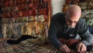 A skilled craftsman repairing a rug with colorful yarns at Ko-Z-Craft in Los Angeles, CA.