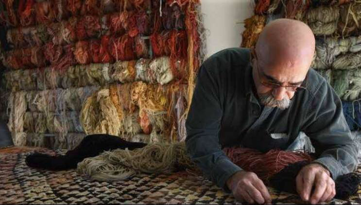 A skilled craftsman repairing a rug with colorful yarns at Ko-Z-Craft in Los Angeles, CA.