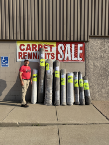 A man standing proudly next to rolls of carpet remnants for sale at Mozak's Floors & More in Yankton, SD