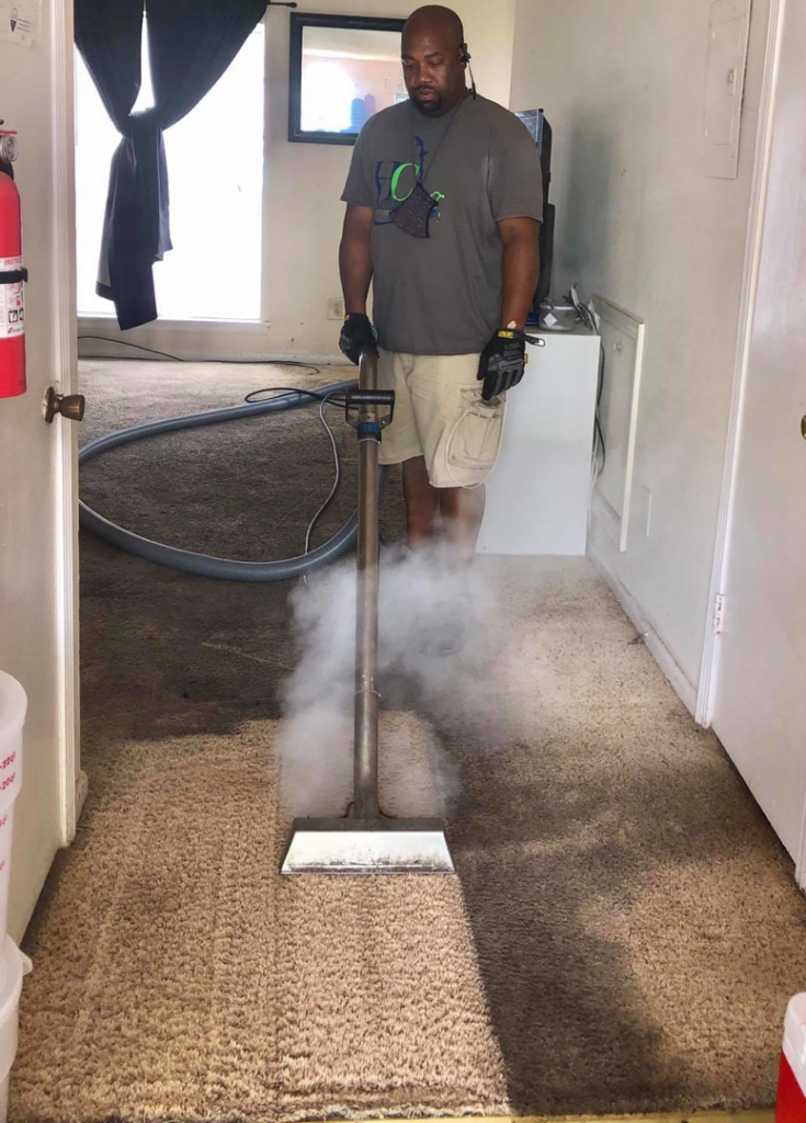A man steam cleaning a carpet in a doorway area, showcasing services by Harper's Carpet & Upholstery Cleaning in San Antonio, FL.