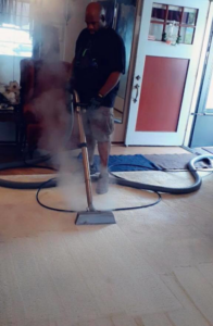 A man steam cleaning a carpet in a home, demonstrating services by Harper's Carpet & Upholstery Cleaning in San Antonio, FL.