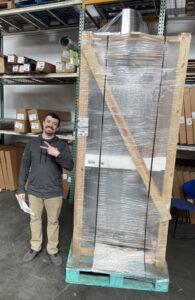 A man standing next to a large, crated HVAC furnace unit at Winsupply of Kansas City in North Kansas City, MO.