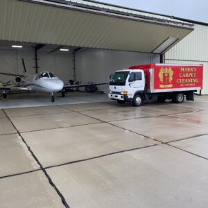 Mark's Carpet Cleaning truck parked next to a private jet inside a hangar in Omaha, NE