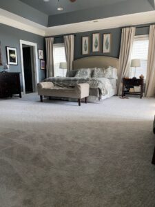 A spacious master bedroom with new light grey wall-to-wall carpet installed by Floorboys of Greenville in Greenville, SC.