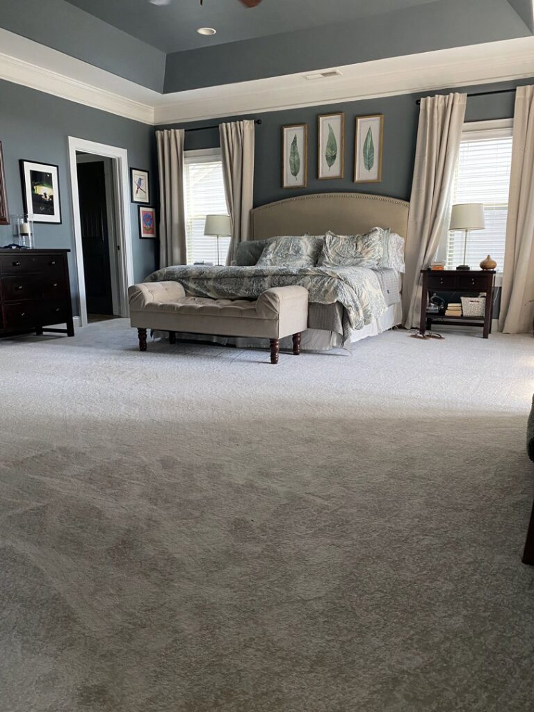 A spacious master bedroom with new light grey wall-to-wall carpet installed by Floorboys of Greenville in Greenville, SC.