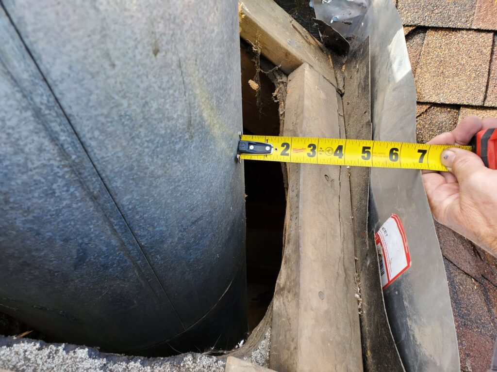 A technician measuring a chimney pipe on a roof, part of a service by Midtown Chimney Sweeps in Golden, CO.