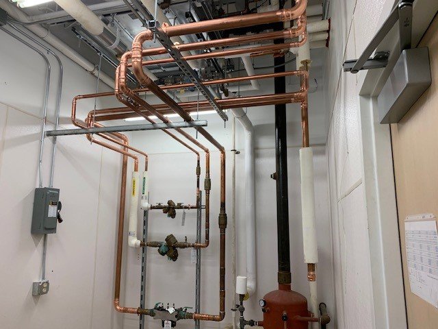 A mechanical room with extensive copper piping and heating system components installed by CM3, Inc. in Wichita, KS.