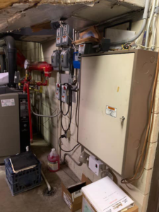 A mechanical room showing hydronic heating pipes and an electrical panel serviced by Allstate Heating & Cooling in Lexington, KY.