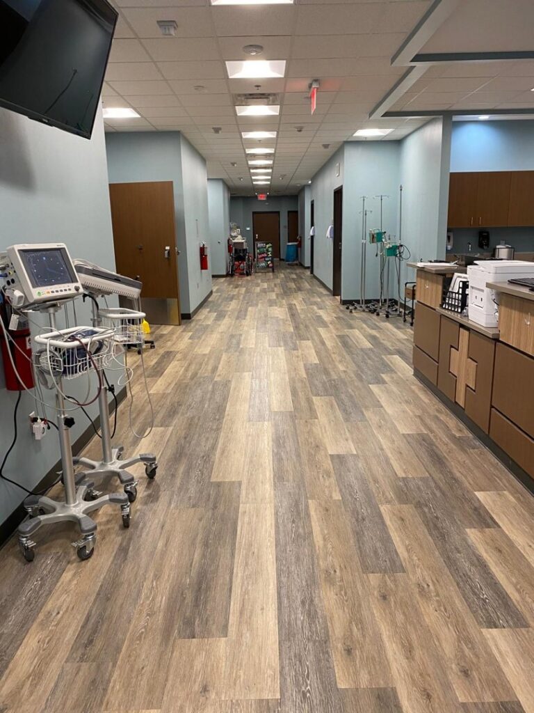 A long hallway in a medical facility with wood-look plank flooring installed by Carpet World Baton Rouge, LA.