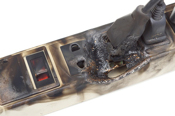 A close-up of a melted and burnt power strip, indicating an electrical hazard, addressed by BT Electric LLC in Gillette, WY.