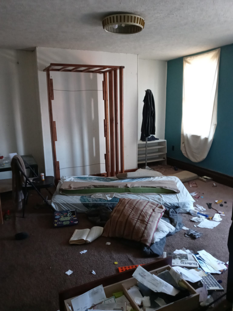 A messy bedroom with old, dirty brown carpet, ready for replacement or cleaning by Stubborn Bull Contracting in Pittsburgh, PA.