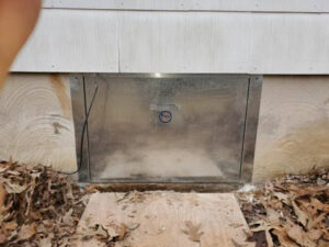 A metal access panel installed on a house foundation for wildlife exclusion by K.P. Wildlife Control and Repairs LLC in Annapolis, MD.