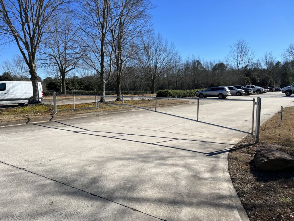 A simple metal barrier gate across a driveway with a chain link fence by Gates Contractors in Plymouth, MN.