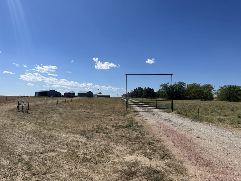 A metal entrance gate and archway leading to a property, a completed project by Cool Hand Fencing and Wyo War Wagons in Laramie, WY.